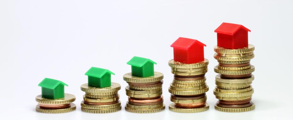 Hausmodelle auf steigenden Münzstapeln – Marktwertermittlung